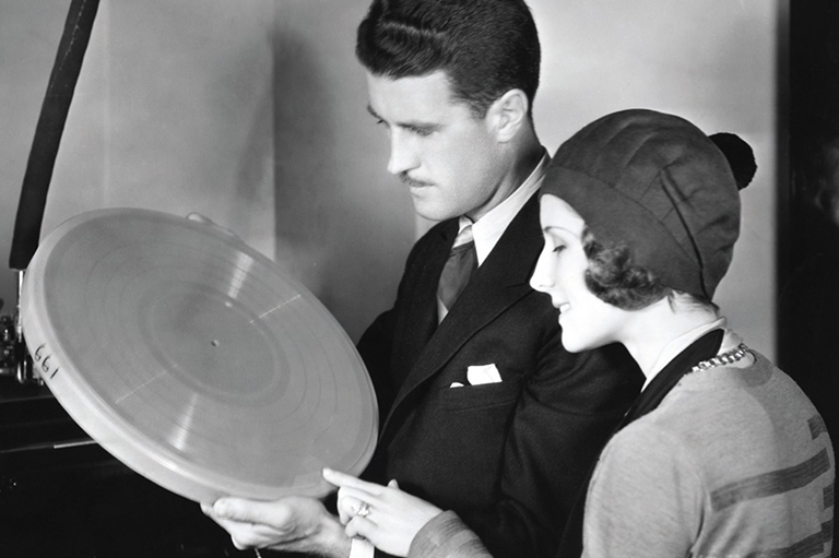 A man and a woman holding a disk, both are looking to the left at the disk. 