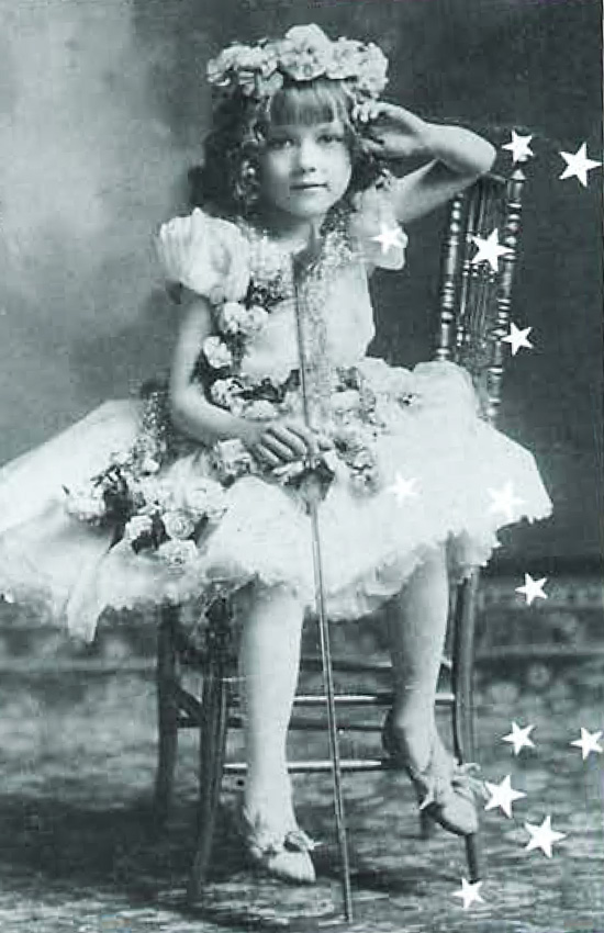 a young girl with bangs, a flower crown, and a white dress sitting in a chair. 
