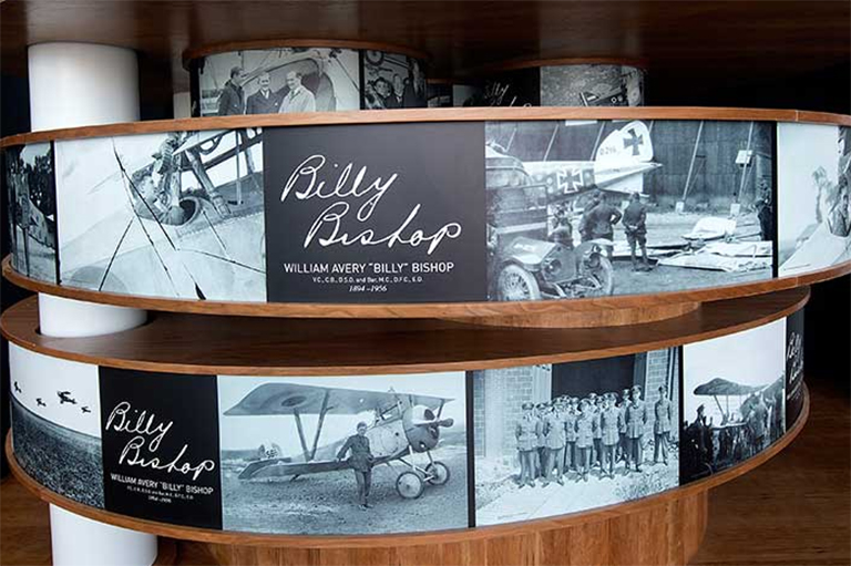 Exhibit display showing historical black-and-white photographs of airplanes.