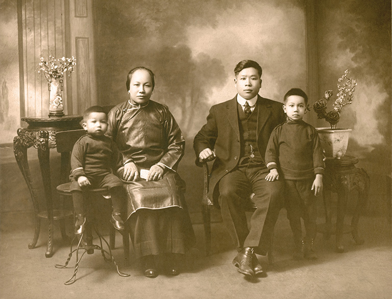 Two adults sitting in chairs, and a child on each side.