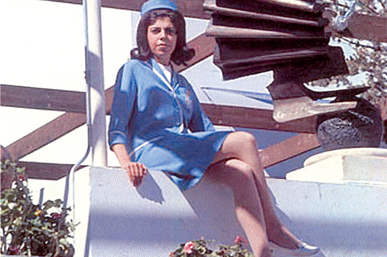 Woman in modern blue uniform sitting cross-legged.