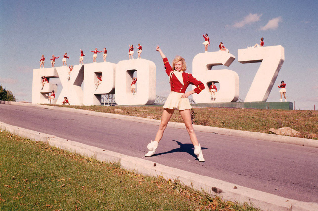 Majorettes standing on large Expo 67 sign.