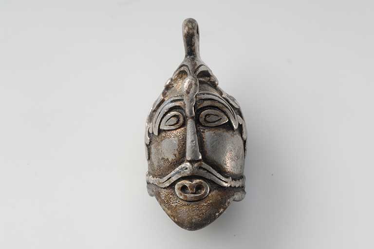 This image shows a silver pendant in the shape of a male head.