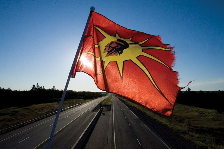 red flag against blue sky and sunlight coming through the flag.