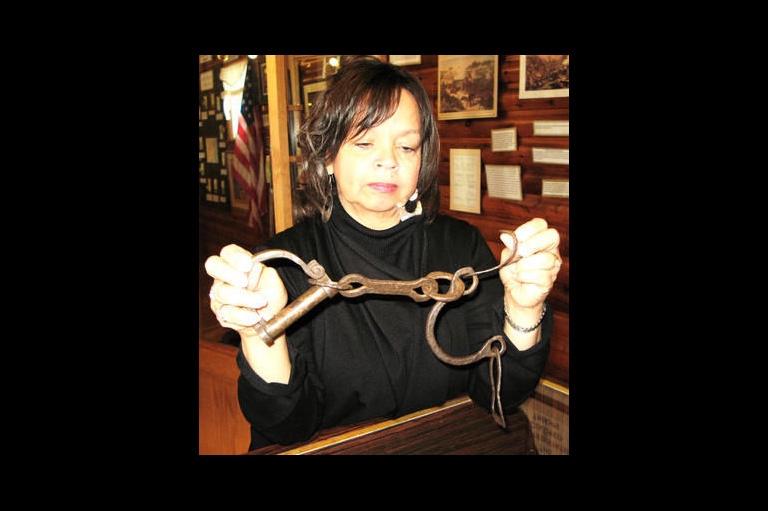 Curator Shannon Prince holds up shackles used on slaves.