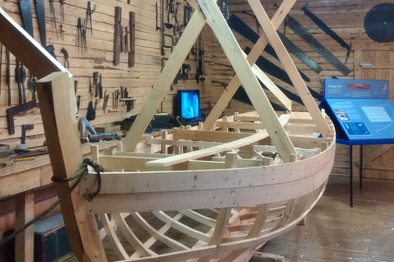This image shows the wooden frame of a boat in a building.