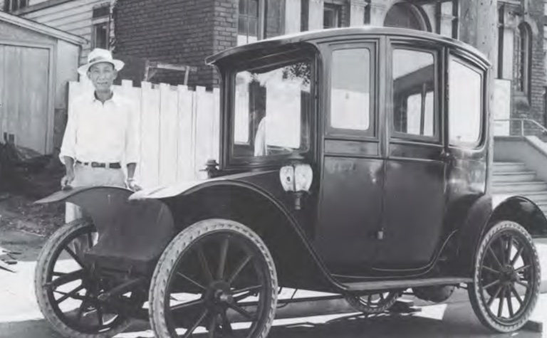 Black and white photo of a man standing next to a Hupp-Yeats model vehicle.