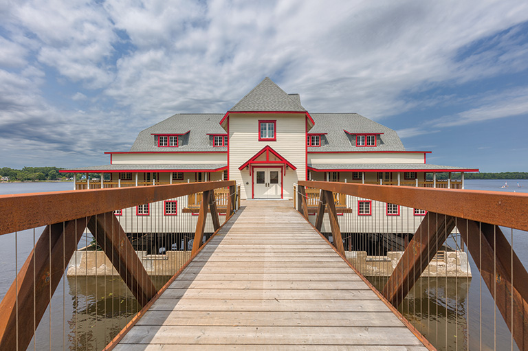 A boardwalk leads to the entrance to a boathouse on the water.