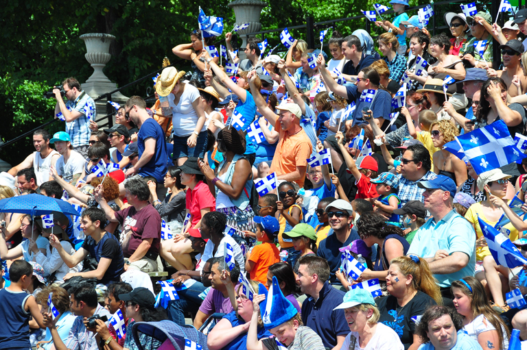 A crowd of people waving Quebec flags