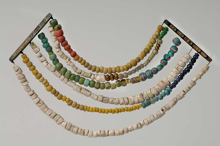 This image shows bronze, glass, and gold beads in a set of six rows. 