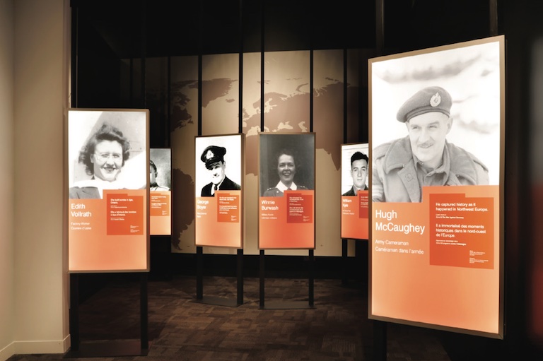 Exhibit panels show black and white portraits above and text on an orange background below.