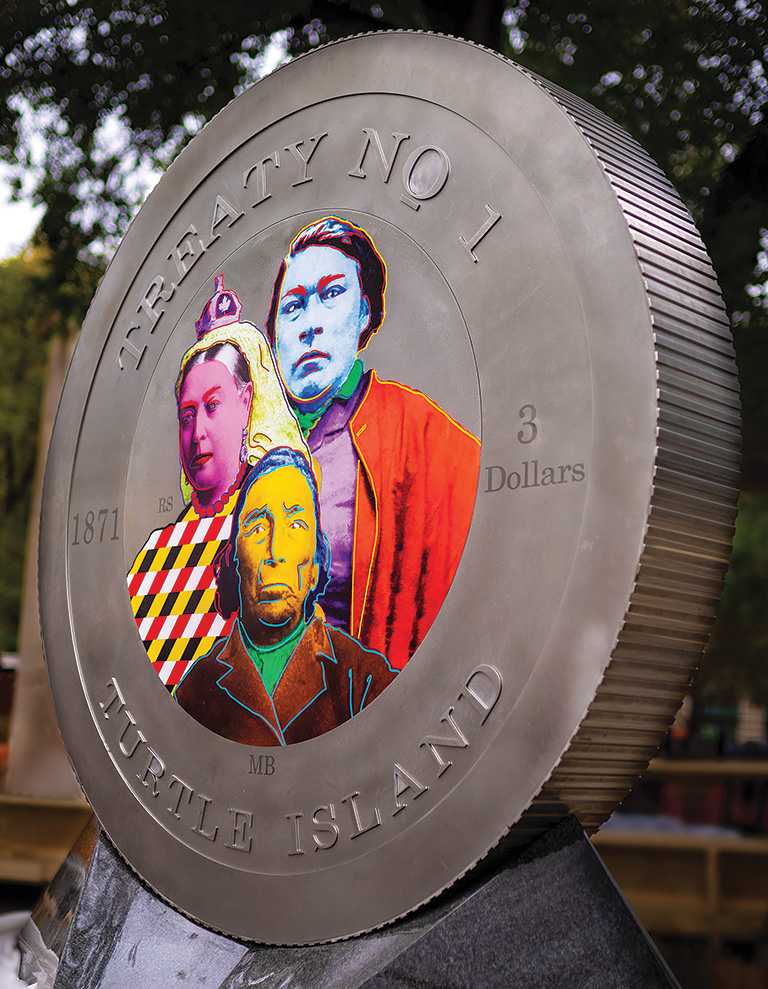 Large replica of a coin with three colourful portraits in the centre.