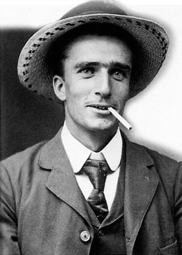 Man wearing a suit and a hat smoking a cigarette 