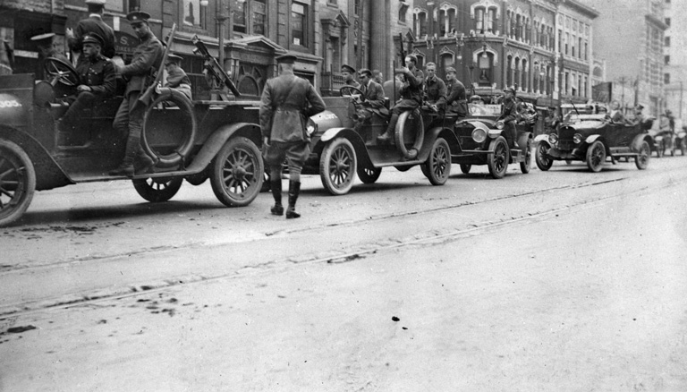 A line up of cars with police men sitting in them.