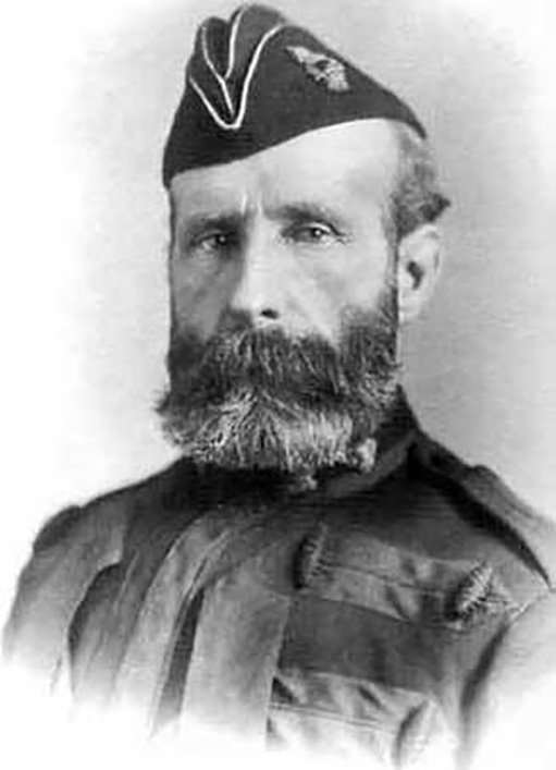 A greyscale image of a bearded man wearing a hat and uniform. 