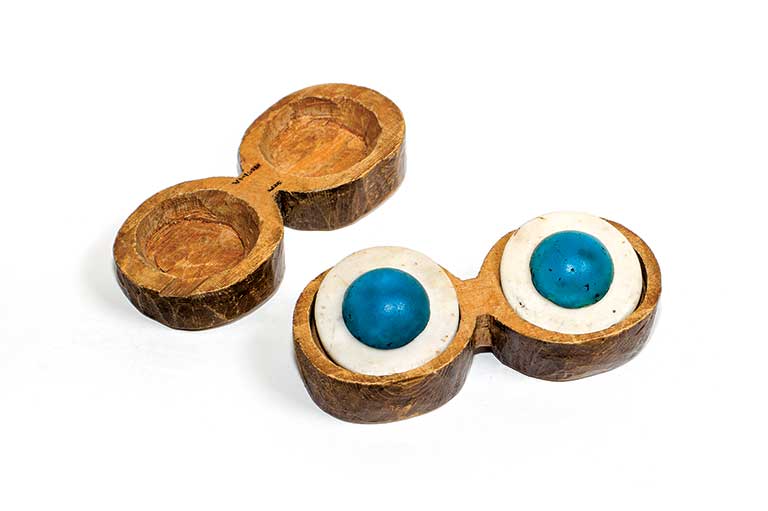 A wooden case for two pieces of jewellery has the lid open to display the objects. The jewellery is composed of two white semi-circles with bright blue centres.