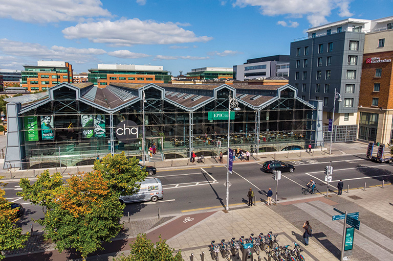 An aerial view of an old market structure with glass panelling across the front. The structure has posters advertising museum exhibitions.