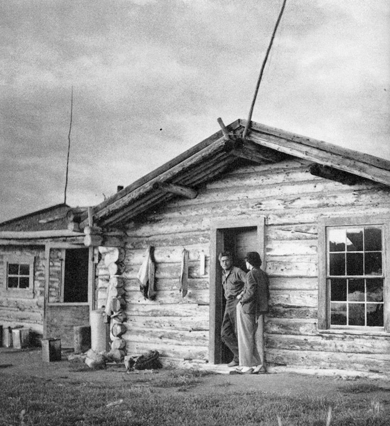 two people stand in the doorway of a cabin