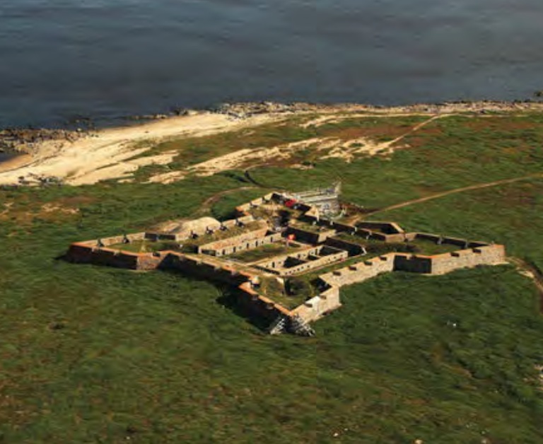 An aerial view of an old stone fort shows its geometric shape on a large grassy hill.