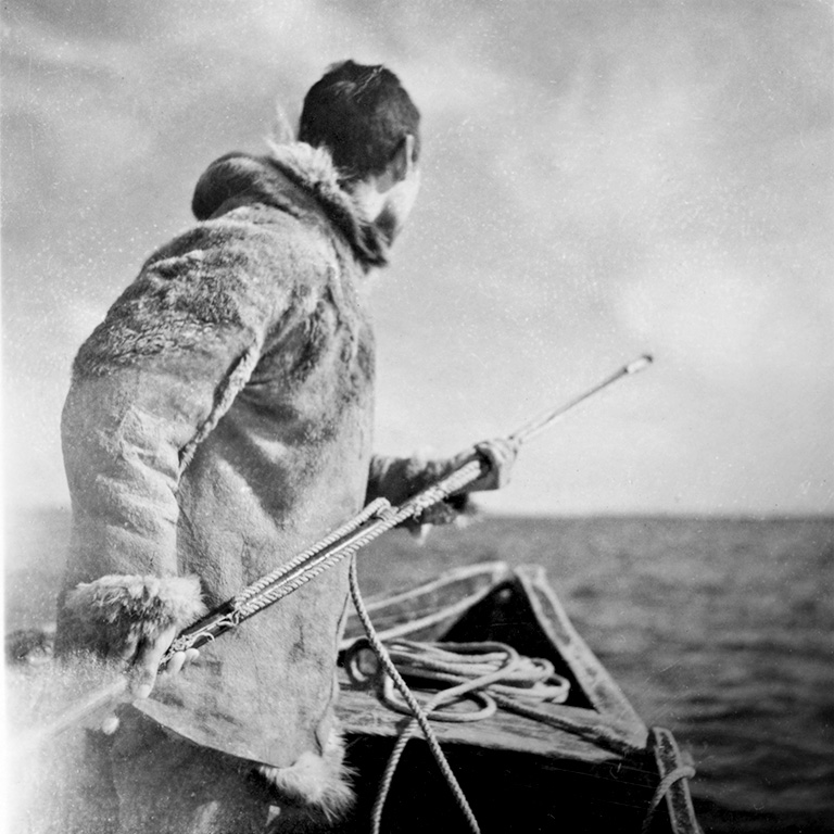 A man in a parka holds a harpoon.
