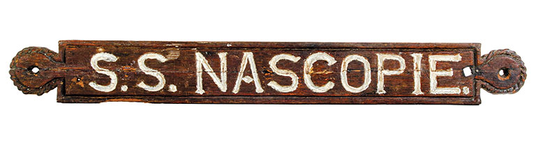 Photo of a wooden nameplate for a ship that reads "S.S. Nascopie" in white lettering.