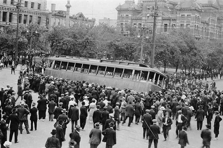 A crowd of people pushing over a streetcar.