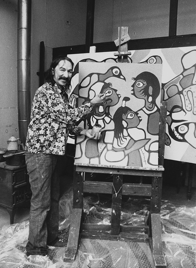Black and white photo of an artist in a floral shirt standing beside an easel and putting a paintbrush on a partially finished painting.