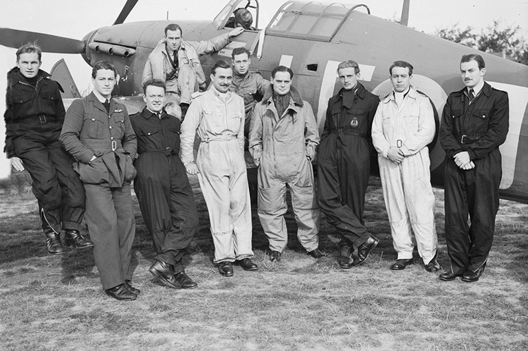 This image shows a group of men in uniforms leaning against an airplane 
