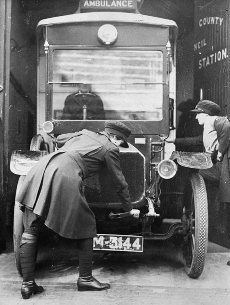 Woman cranks up engine while another woman climbs into the ambulance.