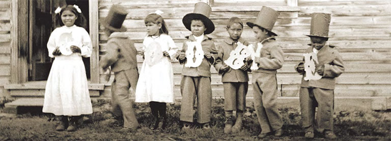 Seven young childrean in "finest dress" costumes, holding letter that spell goodbye. 