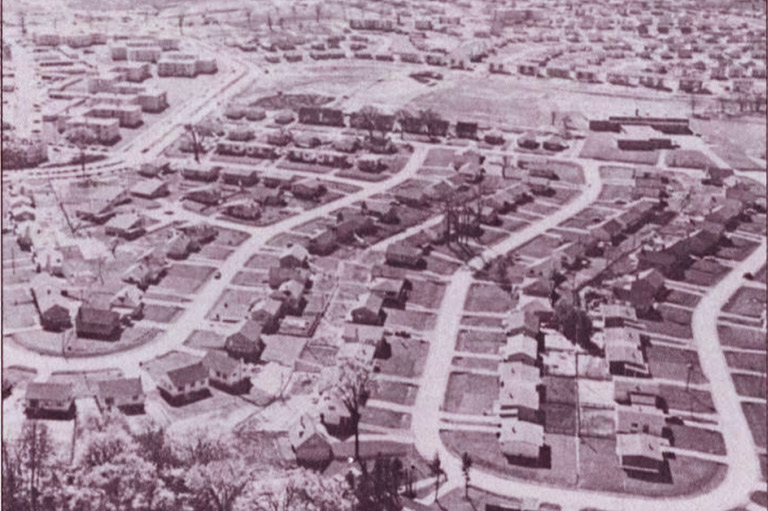 A gray-scale image of a suburban neighbourhood showing similar looking houses side-by-side.  