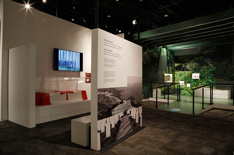 Photo of the interior of an exhibition featuring a display with a coffin covered in a Canadian flag.