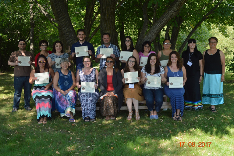 Group of people standing outside holding certificates. 